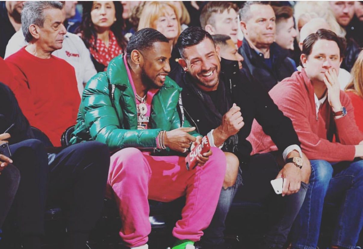 Two guests seated courtside at a basketball game